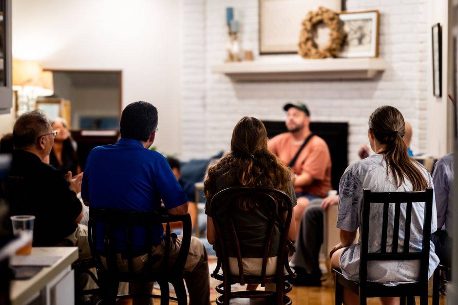 A diverse group engages in a casual conversation in a cozy living room setting.