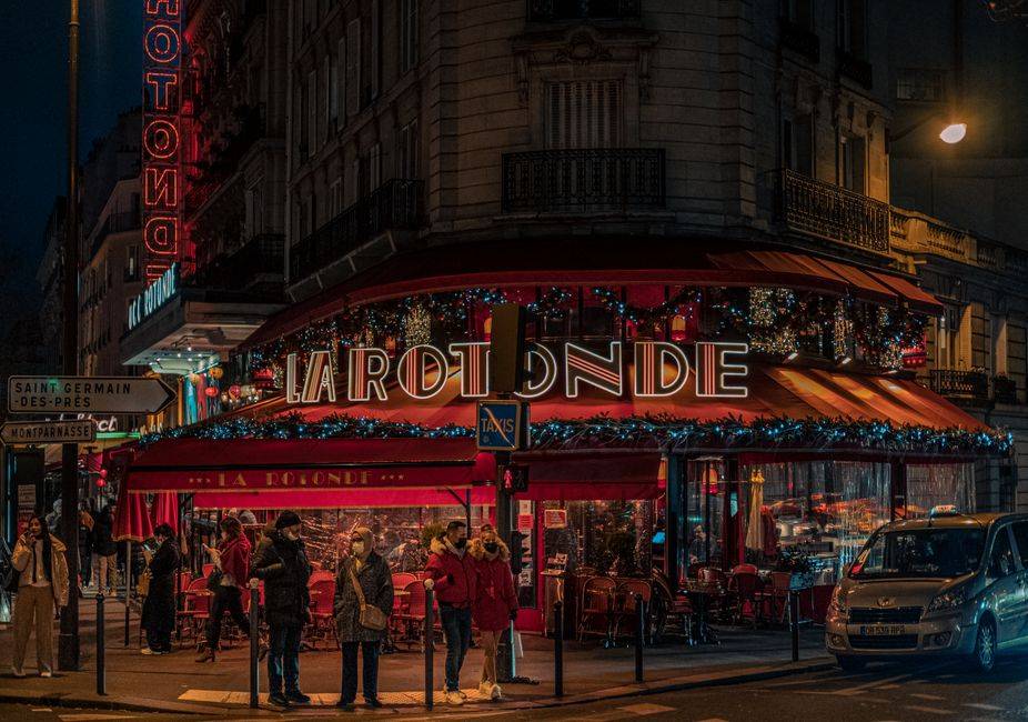 A vibrant view of La Rotonde café on a bustling night in Paris, France.