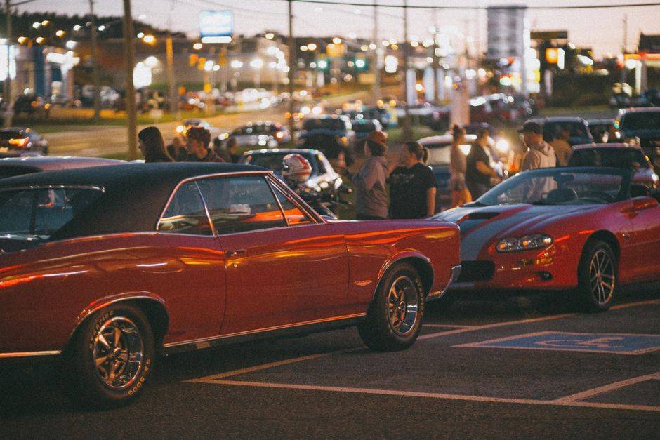A lively gathering of classic car enthusiasts showcasing vintage models at night.